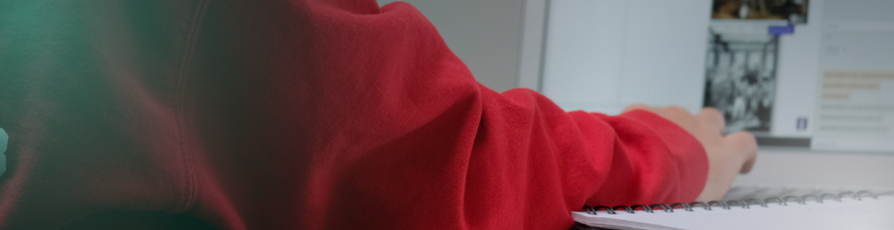 Young student in red hoodie using a laptop for online learning